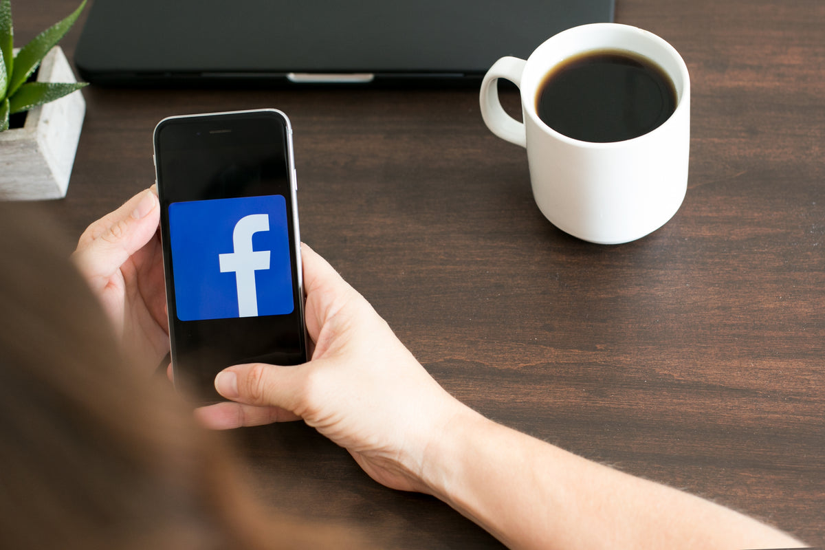 a person holding a phone with a facebook logo on it